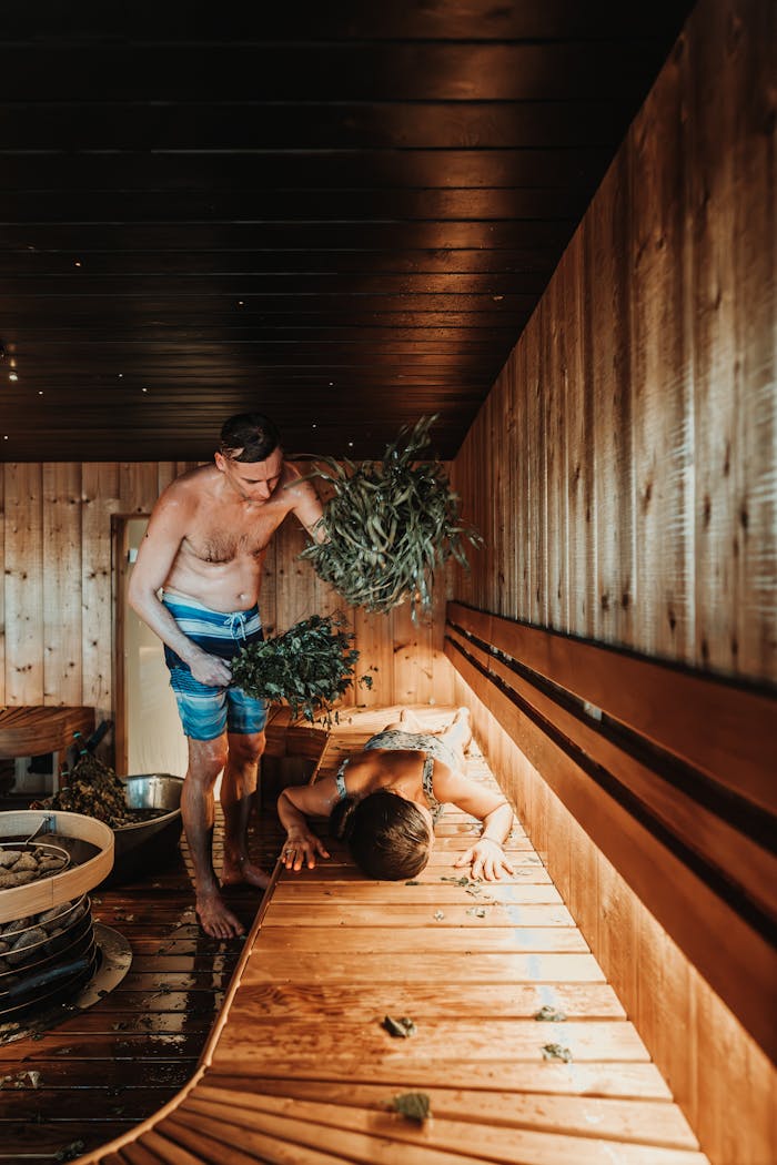 Two men engaging in a traditional Nordic sauna whisking ritual, capturing relaxation and wellness.