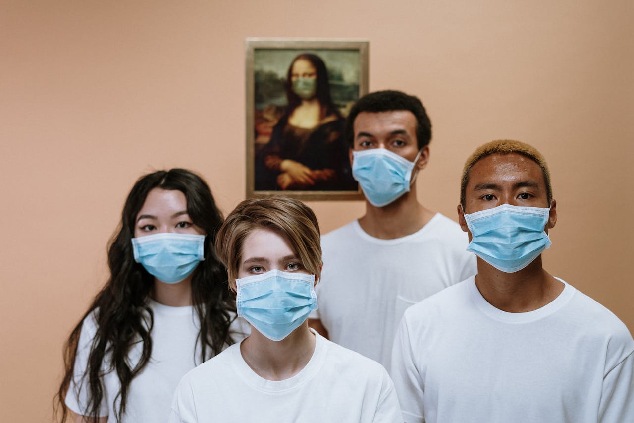 our-story A diverse group wearing masks stands in front of a masked Mona Lisa painting.